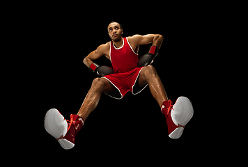 Image showing Young african-american boxer in action, motion isolated on black background, look from the bottom. Concept of sport, movement, energy and dynamic.