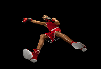 Image showing Young african-american boxer in action, motion isolated on black background, look from the bottom. Concept of sport, movement, energy and dynamic.