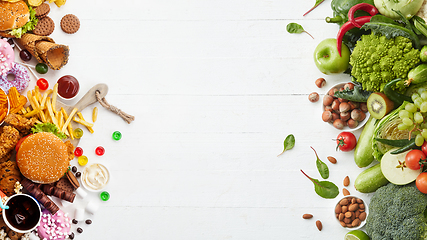 Image showing Fast and healthy food compared on white background. Unhealthy set including burgers, sauces, french fries in comparison with vegetables, fruits, organic food