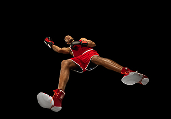 Image showing Young african-american boxer in action, motion isolated on black background, look from the bottom. Concept of sport, movement, energy and dynamic.