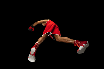 Image showing Young african-american boxer in action, motion isolated on black background, look from the bottom. Concept of sport, movement, energy and dynamic.