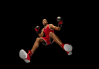 Image showing Young african-american boxer in action, motion isolated on black background, look from the bottom. Concept of sport, movement, energy and dynamic.