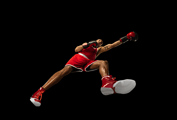 Image showing Young african-american boxer in action, motion isolated on black background, look from the bottom. Concept of sport, movement, energy and dynamic.