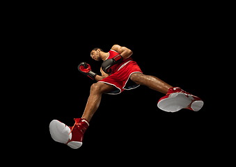 Image showing Young african-american boxer in action, motion isolated on black background, look from the bottom. Concept of sport, movement, energy and dynamic.