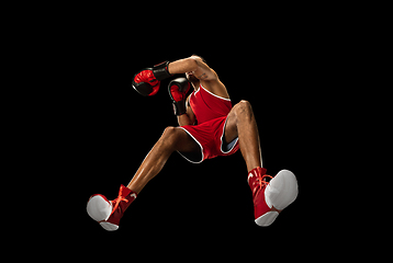 Image showing Young african-american boxer in action, motion isolated on black background, look from the bottom. Concept of sport, movement, energy and dynamic.