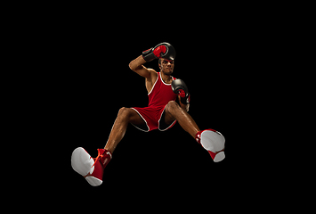 Image showing Young african-american boxer in action, motion isolated on black background, look from the bottom. Concept of sport, movement, energy and dynamic.