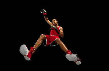 Image showing Young african-american boxer in action, motion isolated on black background, look from the bottom. Concept of sport, movement, energy and dynamic.