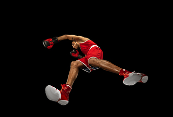 Image showing Young african-american boxer in action, motion isolated on black background, look from the bottom. Concept of sport, movement, energy and dynamic.