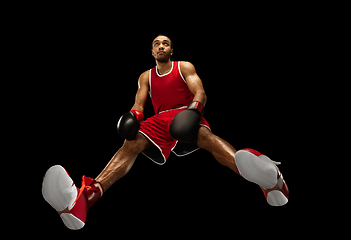 Image showing Young african-american boxer in action, motion isolated on black background, look from the bottom. Concept of sport, movement, energy and dynamic.