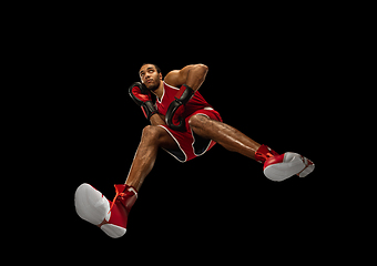 Image showing Young african-american boxer in action, motion isolated on black background, look from the bottom. Concept of sport, movement, energy and dynamic.