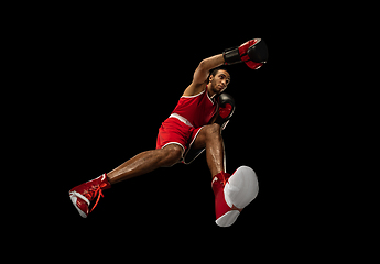 Image showing Young african-american boxer in action, motion isolated on black background, look from the bottom. Concept of sport, movement, energy and dynamic.