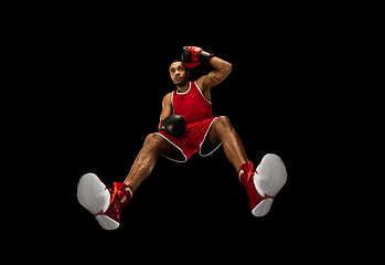 Image showing Young african-american boxer in action, motion isolated on black background, look from the bottom. Concept of sport, movement, energy and dynamic.