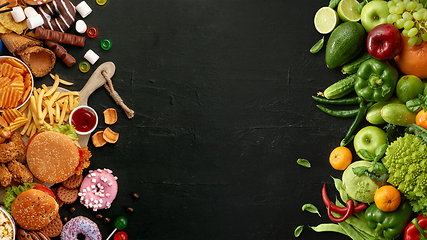 Image showing Fast and healthy food compared on black stone background. Unhealthy set including burgers, sauces, french fries in comparison with vegetables, fruits, organic food