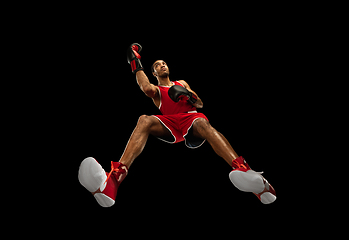 Image showing Young african-american boxer in action, motion isolated on black background, look from the bottom. Concept of sport, movement, energy and dynamic.