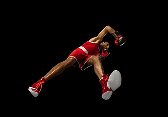 Image showing Young african-american boxer in action, motion isolated on black background, look from the bottom. Concept of sport, movement, energy and dynamic.