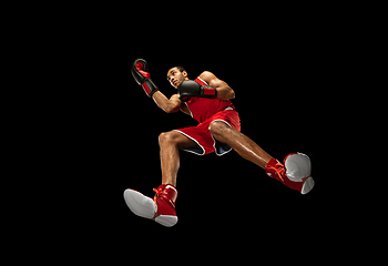 Image showing Young african-american boxer in action, motion isolated on black background, look from the bottom. Concept of sport, movement, energy and dynamic.