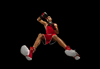 Image showing Young african-american boxer in action, motion isolated on black background, look from the bottom. Concept of sport, movement, energy and dynamic.