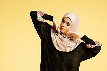 Image showing Beautiful arab woman posing in stylish hijab isolated on yellow studio background. Fashion, beauty, style concept