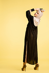 Image showing Beautiful arab woman posing in stylish hijab isolated on yellow studio background. Fashion, beauty, style concept