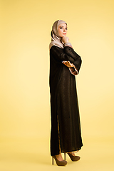 Image showing Beautiful arab woman posing in stylish hijab isolated on yellow studio background. Fashion, beauty, style concept