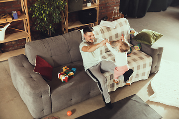 Image showing Young man exercising fitness, aerobic, yoga at home, sporty lifestyle. Getting active while his child playing on the background, home gym.