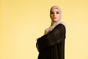 Image showing Beautiful arab woman posing in stylish hijab isolated on yellow studio background. Fashion, beauty, style concept