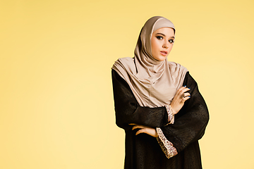 Image showing Beautiful arab woman posing in stylish hijab isolated on yellow studio background. Fashion, beauty, style concept