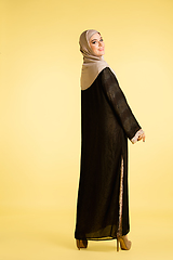 Image showing Beautiful arab woman posing in stylish hijab isolated on yellow studio background. Fashion, beauty, style concept