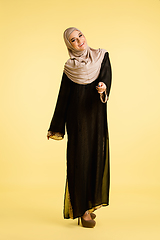 Image showing Beautiful arab woman posing in stylish hijab isolated on yellow studio background. Fashion, beauty, style concept