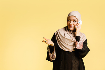 Image showing Beautiful arab woman posing in stylish hijab isolated on yellow studio background. Fashion, beauty, style concept