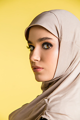 Image showing Beautiful arab woman posing in stylish hijab isolated on yellow studio background. Fashion, beauty, style concept