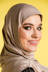 Image showing Beautiful arab woman posing in stylish hijab isolated on yellow studio background. Fashion, beauty, style concept