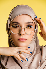 Image showing Beautiful arab woman posing in stylish hijab isolated on yellow studio background. Fashion, beauty, style concept