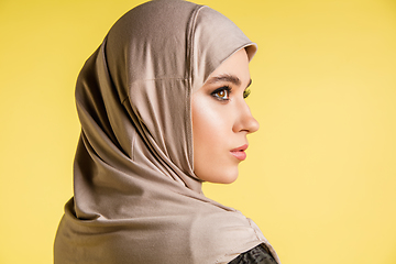 Image showing Beautiful arab woman posing in stylish hijab isolated on yellow studio background. Fashion, beauty, style concept