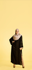 Image showing Beautiful arab woman posing in stylish hijab isolated on yellow studio background. Fashion, beauty, style concept