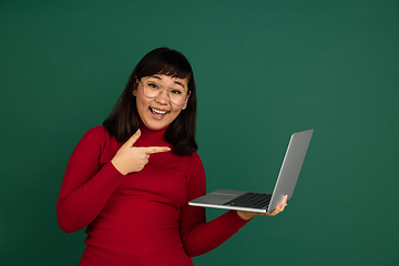 Image showing East asian woman\'s portrait isolated on green studio background with copyspace