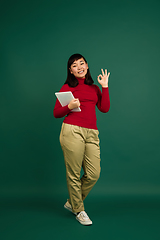 Image showing East asian woman\'s portrait isolated on green studio background with copyspace