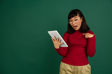 Image showing East asian woman\'s portrait isolated on green studio background with copyspace