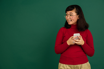 Image showing East asian woman\'s portrait isolated on green studio background with copyspace