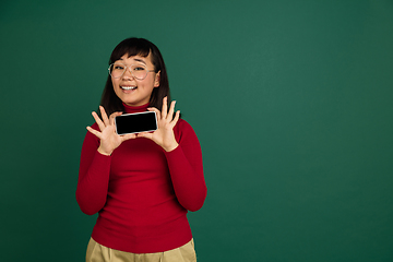 Image showing East asian woman\'s portrait isolated on green studio background with copyspace