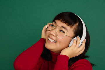 Image showing East asian woman\'s portrait isolated on green studio background with copyspace