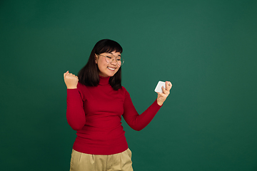 Image showing East asian woman\'s portrait isolated on green studio background with copyspace