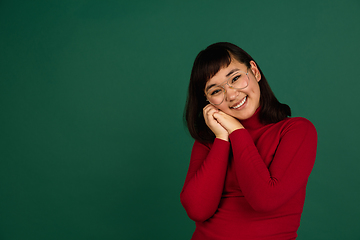 Image showing East asian woman\'s portrait isolated on green studio background with copyspace