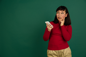 Image showing East asian woman\'s portrait isolated on green studio background with copyspace