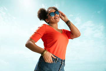 Image showing Portrait of female fashion model on blue sky background. Style and beauty concept, bright appearance