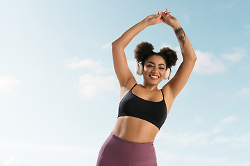 Image showing Portrait of female fashion model on blue sky background. Style and beauty concept, bright appearance. Lifestyle sport.