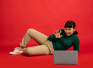 Image showing East asian woman\'s portrait isolated on red studio background with copyspace