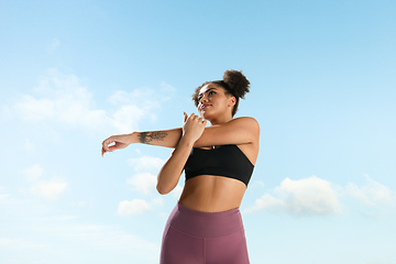 Image showing Portrait of female fashion model on blue sky background. Style and beauty concept, bright appearance. Lifestyle sport.