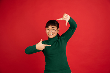 Image showing East asian woman\'s portrait isolated on red studio background with copyspace