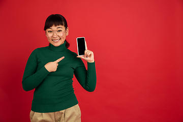 Image showing East asian woman\'s portrait isolated on red studio background with copyspace